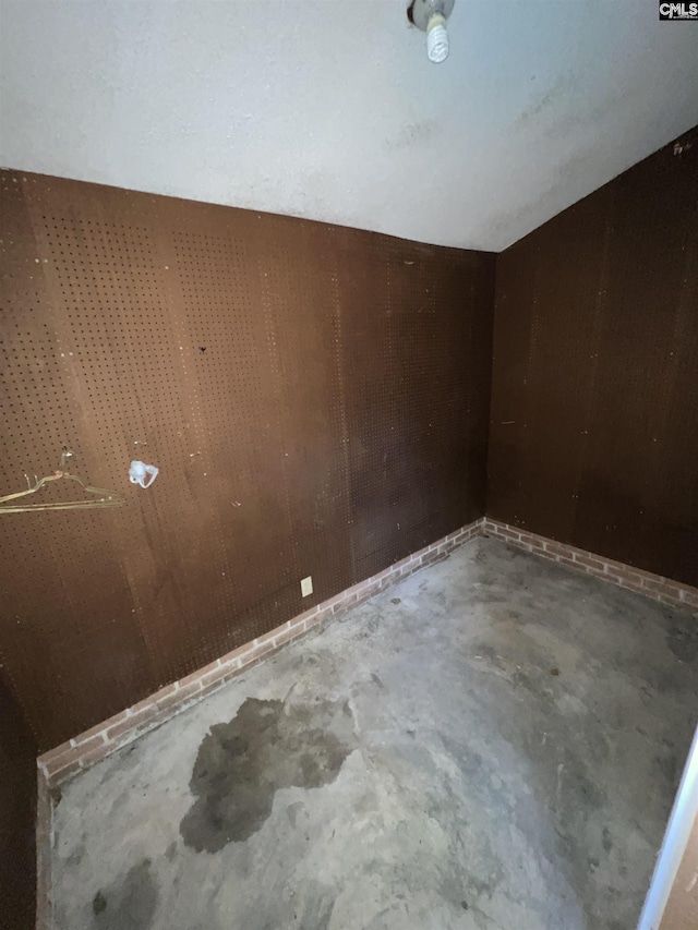 empty room featuring concrete flooring and wooden walls