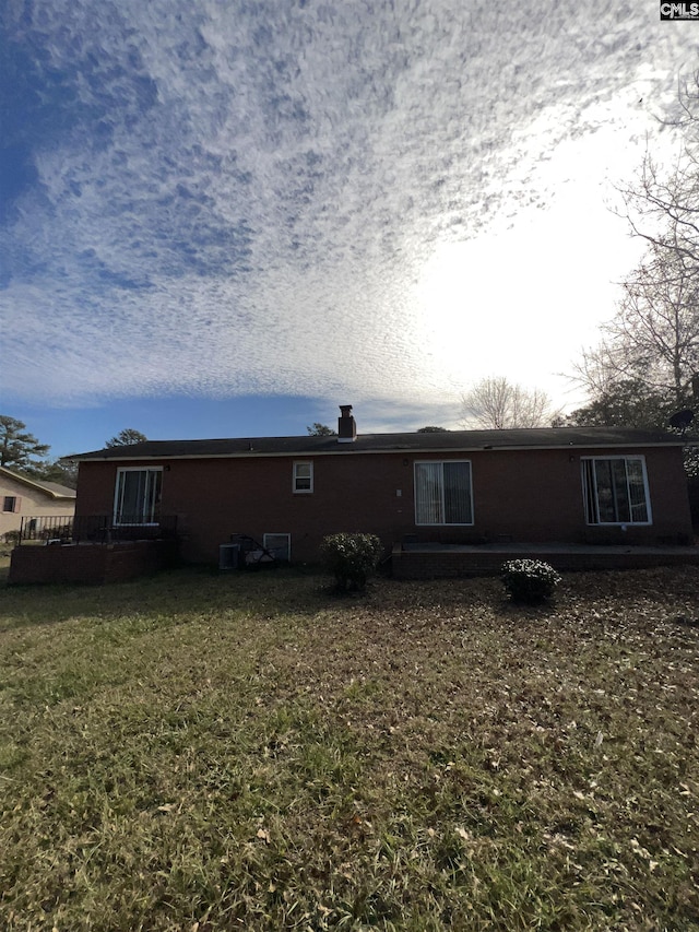 back of property with central air condition unit and a yard