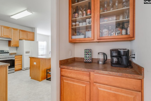 kitchen featuring white refrigerator with ice dispenser and stainless steel range with electric cooktop