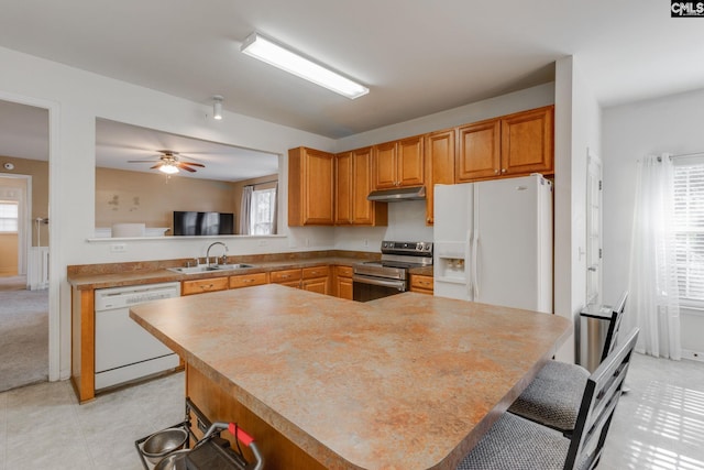 kitchen with white appliances, a kitchen breakfast bar, sink, ceiling fan, and kitchen peninsula