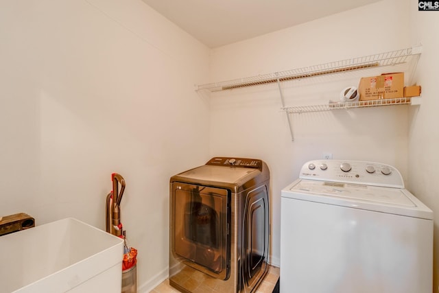 clothes washing area with tile patterned floors, sink, and washer and dryer