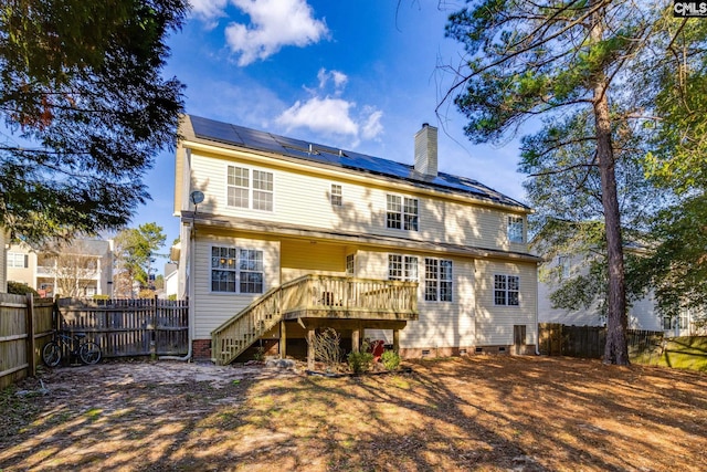 back of property featuring solar panels and a wooden deck