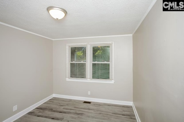 unfurnished room with a textured ceiling, light wood-type flooring, and ornamental molding