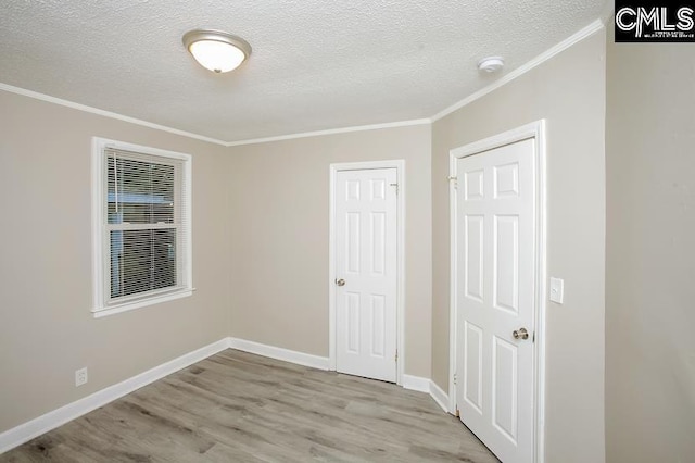 spare room with a textured ceiling, crown molding, and light hardwood / wood-style flooring