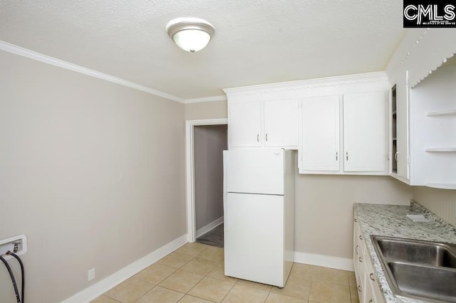 kitchen with white fridge, white cabinetry, ornamental molding, and light tile patterned floors