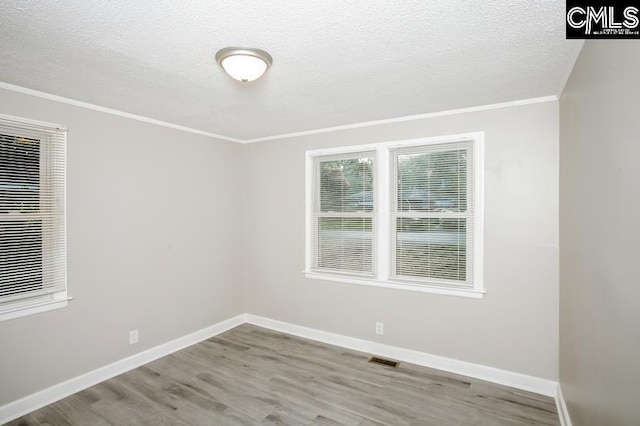 empty room featuring light hardwood / wood-style flooring, a textured ceiling, and ornamental molding