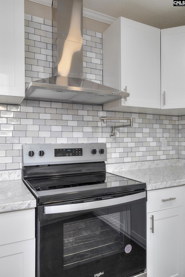 kitchen featuring white cabinets, decorative backsplash, wall chimney range hood, and stainless steel electric range oven