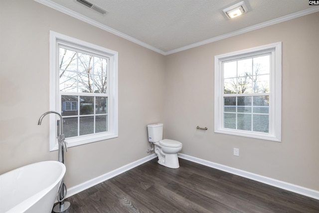 bathroom featuring a bath, crown molding, hardwood / wood-style flooring, toilet, and a textured ceiling