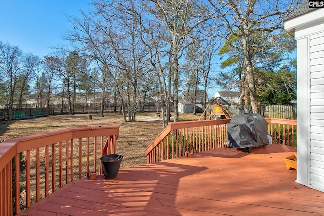 wooden deck featuring area for grilling and a playground