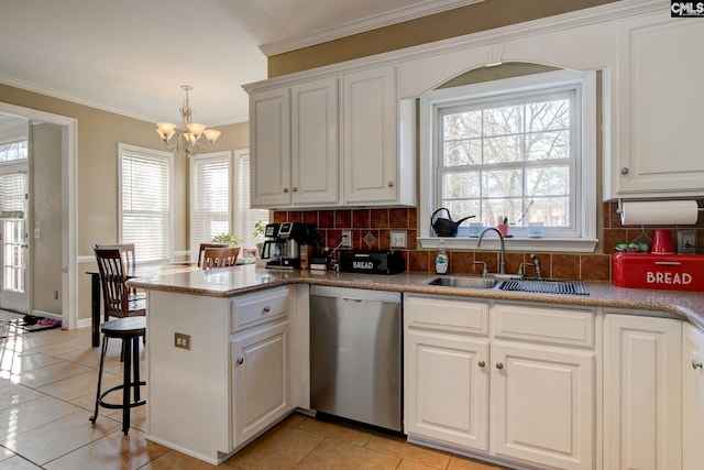 kitchen with dishwasher, white cabinets, sink, light tile patterned floors, and a notable chandelier