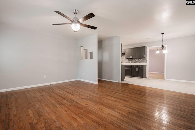 unfurnished living room featuring light hardwood / wood-style flooring and ceiling fan with notable chandelier