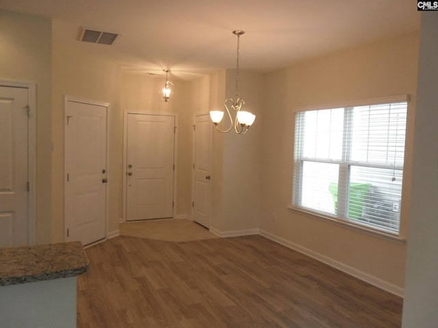 unfurnished dining area featuring a chandelier and dark wood-type flooring