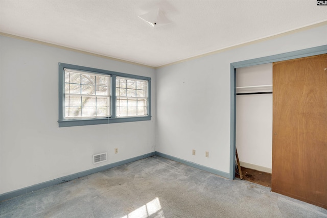 unfurnished bedroom with light carpet, a closet, and ornamental molding