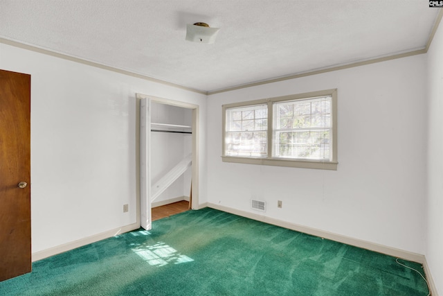 unfurnished bedroom with carpet, a textured ceiling, crown molding, and a closet