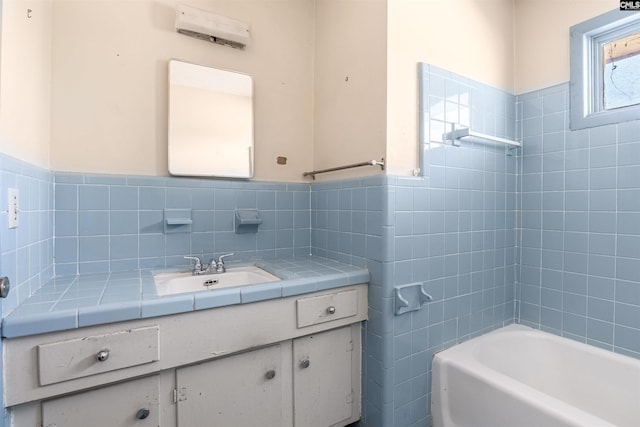 bathroom with a tub, vanity, and tile walls