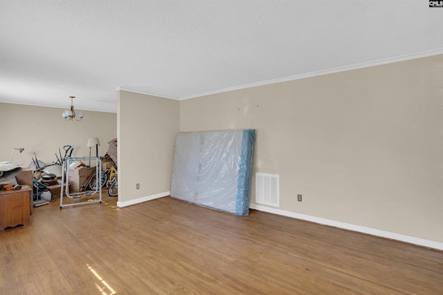 spare room featuring crown molding, a chandelier, and light hardwood / wood-style floors