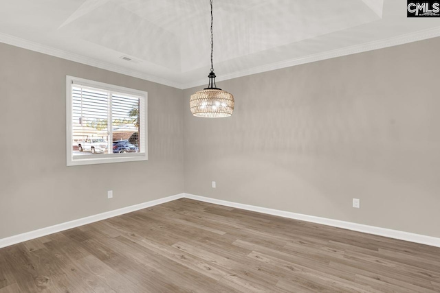 empty room featuring wood-type flooring, a tray ceiling, an inviting chandelier, and crown molding