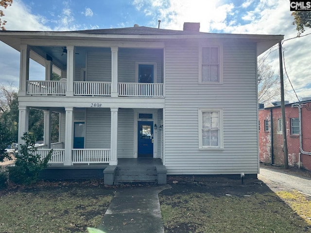 view of front of house featuring a balcony, a porch, and a front yard