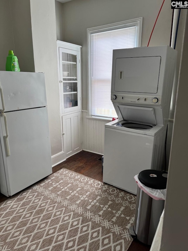 clothes washing area featuring dark hardwood / wood-style floors and stacked washer / dryer