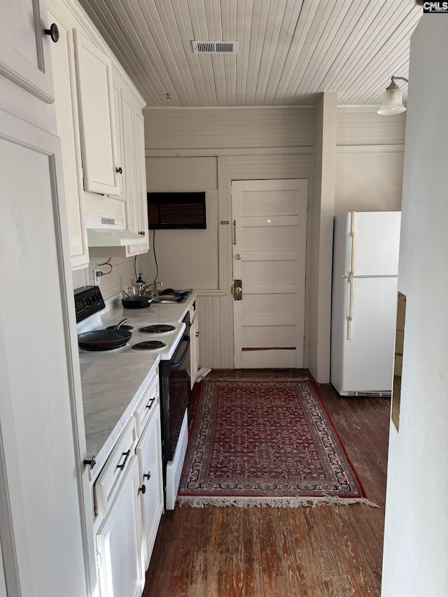 kitchen with extractor fan, white cabinets, dark wood-type flooring, and white appliances