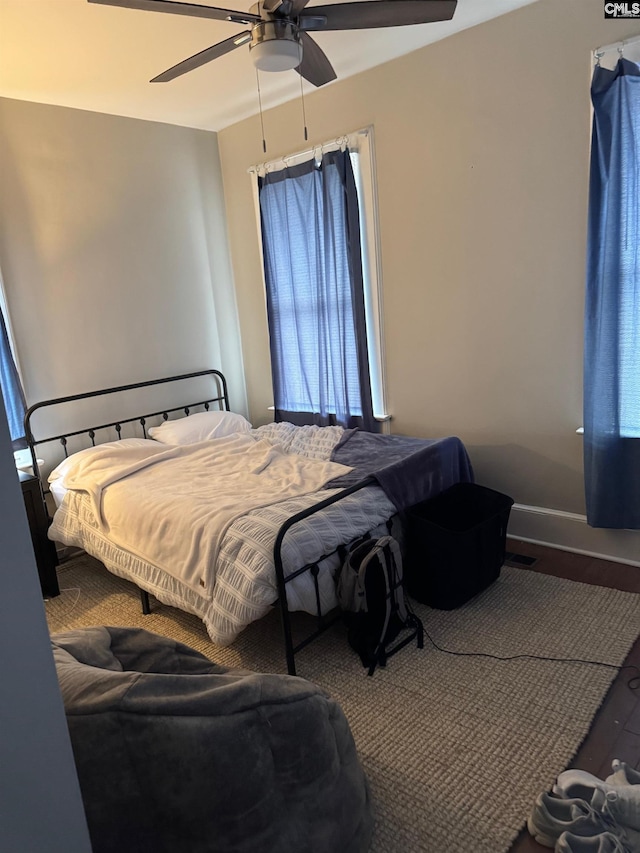 bedroom featuring hardwood / wood-style flooring, ceiling fan, and multiple windows