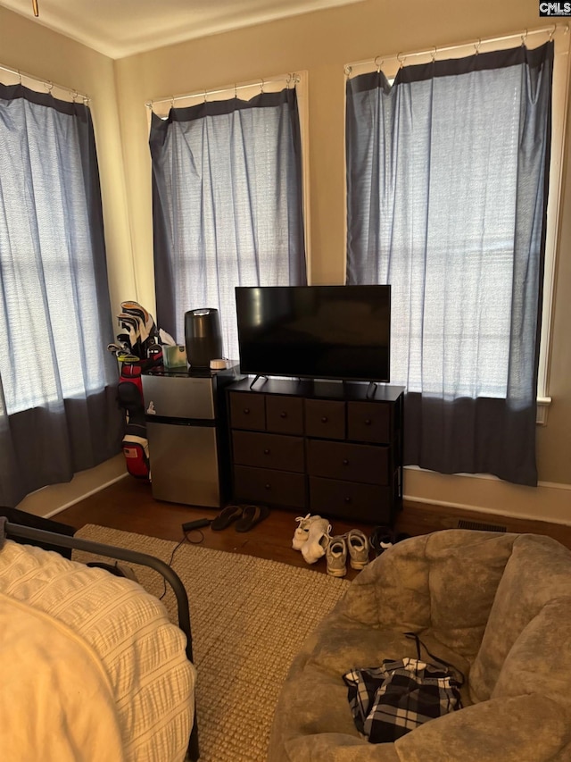 bedroom with stainless steel refrigerator and multiple windows