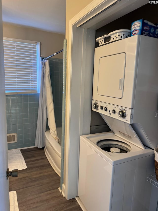 laundry room with dark wood-type flooring and stacked washer and clothes dryer