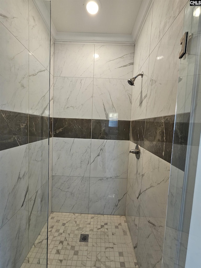 bathroom with a tile shower and ornamental molding