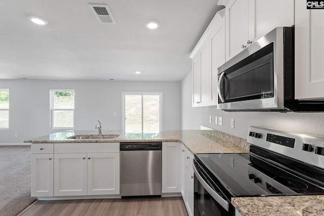 kitchen with kitchen peninsula, appliances with stainless steel finishes, white cabinetry, and sink