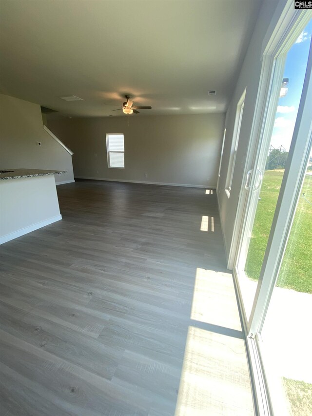 unfurnished living room featuring ceiling fan, a wealth of natural light, and hardwood / wood-style flooring