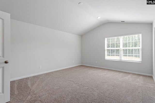 empty room with carpet flooring and vaulted ceiling