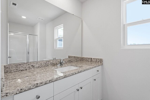 bathroom with toilet, a shower with door, and vanity