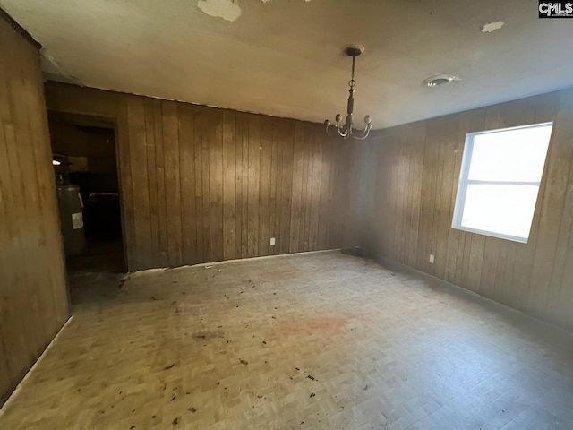 unfurnished dining area featuring a notable chandelier and wood walls