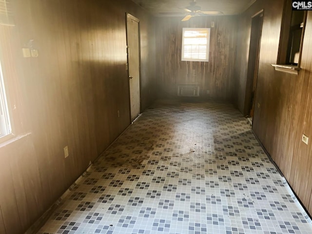 basement with wooden walls, light tile patterned floors, and ceiling fan