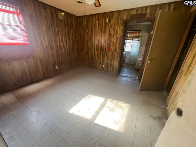 unfurnished room with ceiling fan and wooden walls