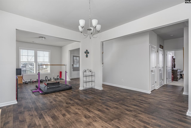 exercise area featuring a notable chandelier and dark wood-type flooring