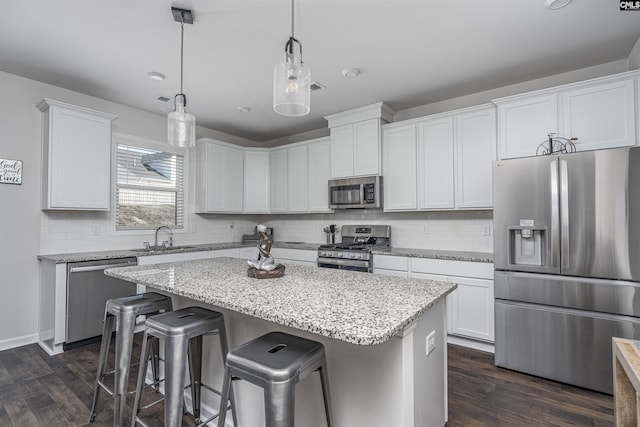 kitchen with white cabinetry, stainless steel appliances, dark hardwood / wood-style flooring, pendant lighting, and a kitchen island