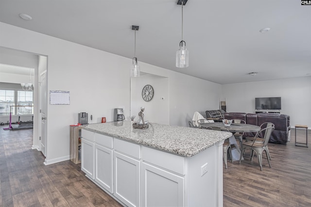 kitchen featuring white cabinets, dark hardwood / wood-style floors, pendant lighting, and light stone counters