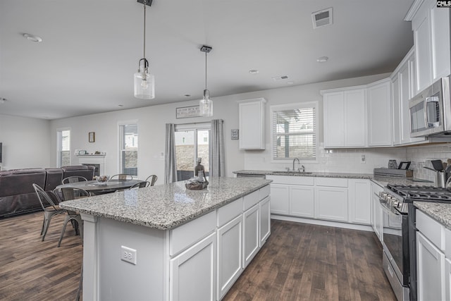 kitchen featuring white cabinets, decorative light fixtures, a kitchen island, and stainless steel appliances