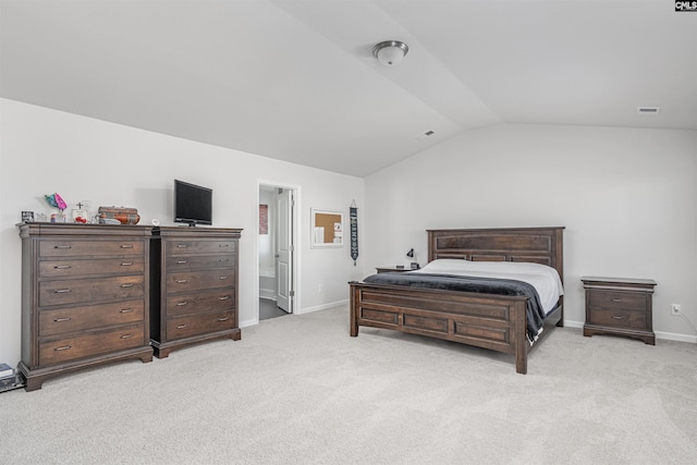 bedroom featuring light carpet, ensuite bathroom, and vaulted ceiling