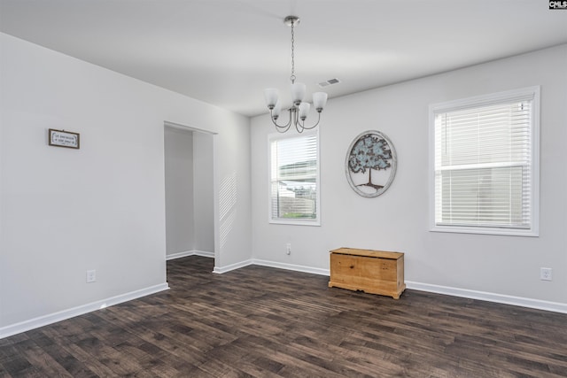 spare room with dark hardwood / wood-style flooring and an inviting chandelier