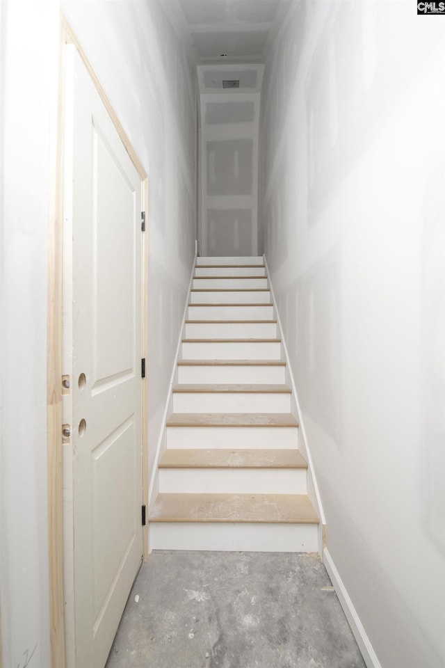 staircase featuring unfinished concrete floors