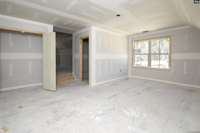 empty room featuring lofted ceiling and baseboards