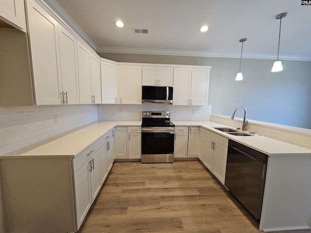 kitchen with white cabinets, sink, hanging light fixtures, light hardwood / wood-style flooring, and stainless steel appliances