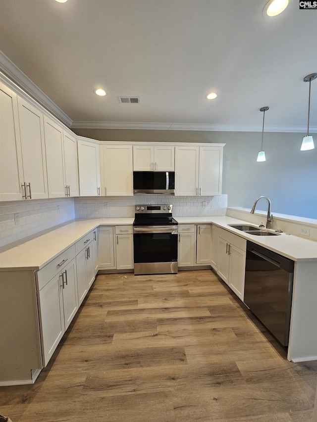 kitchen with kitchen peninsula, appliances with stainless steel finishes, sink, white cabinets, and hanging light fixtures