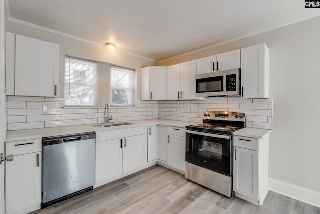 kitchen with decorative backsplash, white cabinetry, sink, and appliances with stainless steel finishes