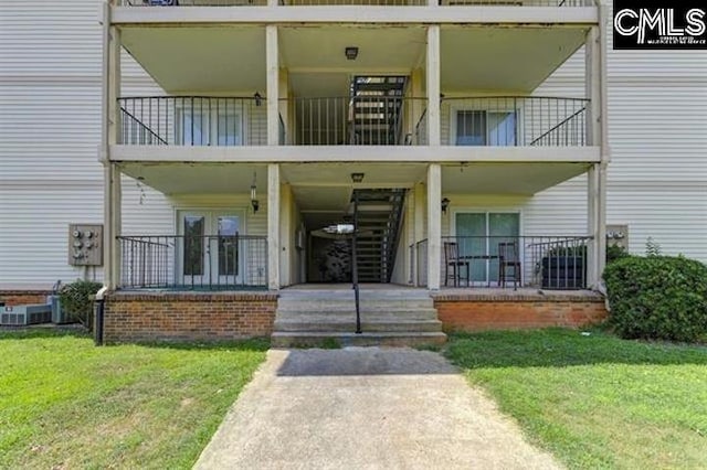 property entrance featuring a lawn, a balcony, and french doors