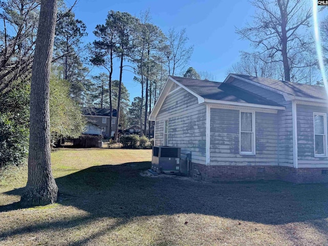 view of side of property with a lawn and central AC unit