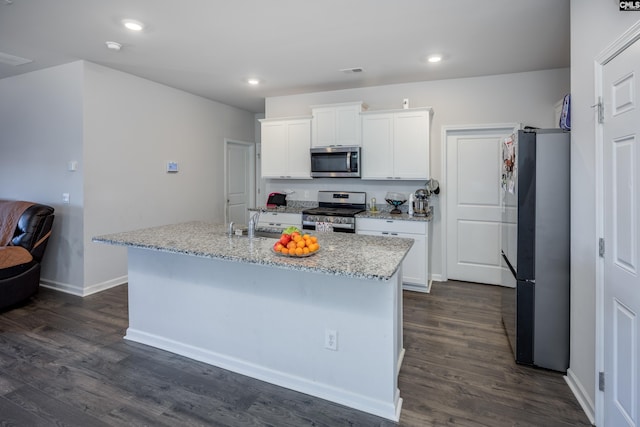 kitchen featuring white cabinets, stainless steel appliances, light stone counters, and a kitchen island with sink