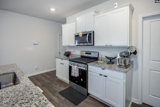 kitchen with white cabinetry, light stone counters, dark hardwood / wood-style floors, and appliances with stainless steel finishes